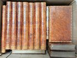 several old books are stacked in a cardboard box on a table