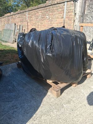a pile of garbage on a pallet next to a brick wall