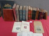 Plusieurs vieux livres sont posés sur une table recouverte d'une nappe rouge.