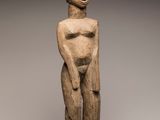 a wooden statue of a woman with a hat on her head