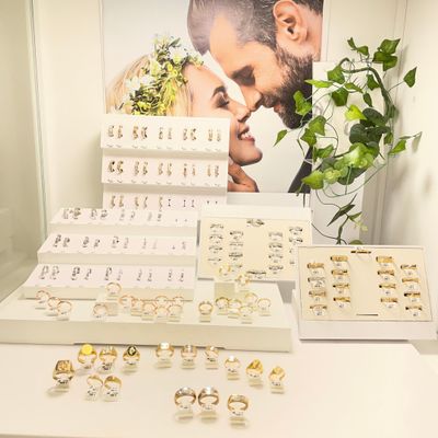 many rings on display on a table in front of a poster