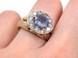 la main d'une femme tenant une bague sertie d'une pierre bleue
