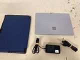 two laptops and a charger sitting on a table