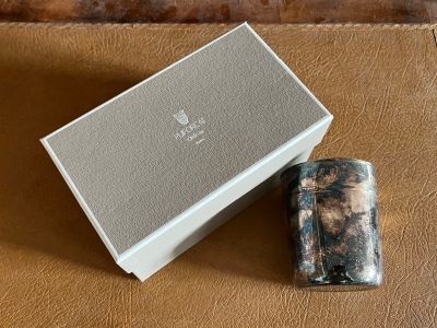 the lighter is next to the box on the leather surface