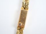 a gold bracelet with a clock on it on a white surface
