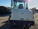 the back end of a white tractor parked in a parking lot