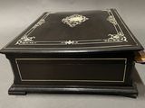 an antique black and gold box with a lid on a table
