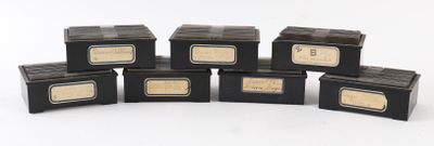 six petites boîtes noires ornées d'étiquettes dorées sont empilées les unes sur les autres