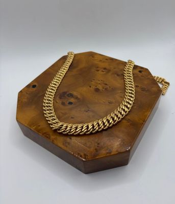 a gold necklace on a wooden stand with a chain