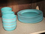 a stack of blue plates and cups on a shelf
