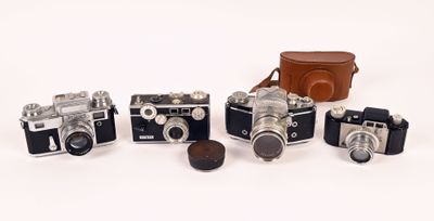 several old cameras are lined up in a row on a white surface
