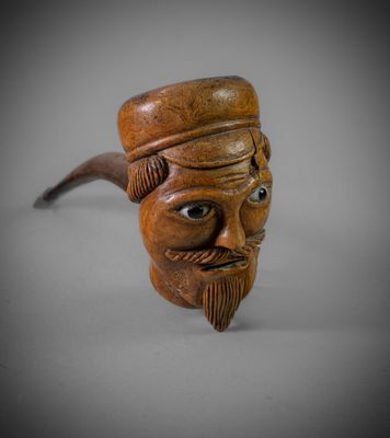 un gros plan d'une pipe en bois sur laquelle est représenté le visage d'un homme