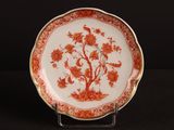 une assiette orange et blanche décorée de fleurs et d'oiseaux