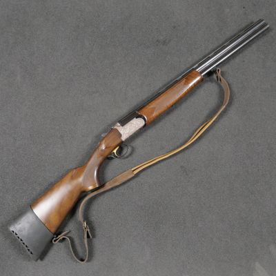 un fusil avec un canon en bois et une bouche métallique, posé sur une surface grise