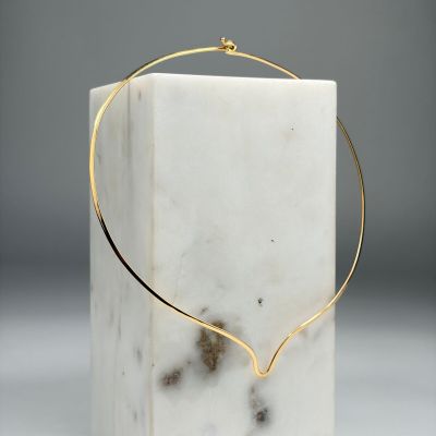un bloc de marbre blanc sur lequel est posé un collier en fil d'or