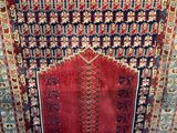 a red and blue rug hanging on a wall