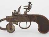 un vieux fusil surmonté d'un homme, posé sur une table