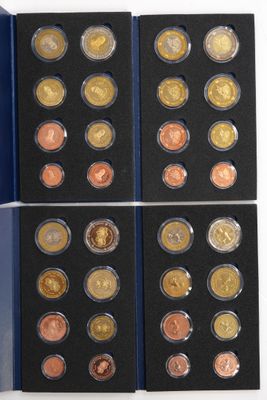a set of six different coins in a blue box on a white surface