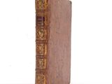 an old book sitting on top of a white table next to a white wall