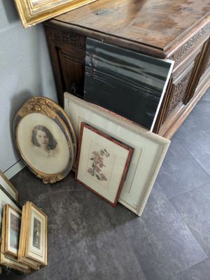 beaucoup de photos encadrées posées par terre à côté d'une commode