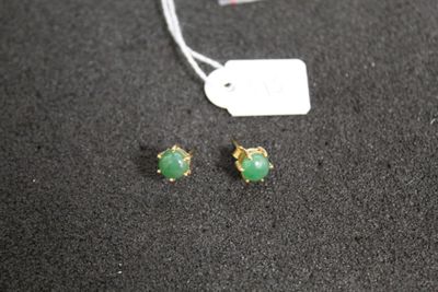 une paire de boucles d'oreilles à clous en pierre verte sur un fond noir