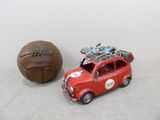 a small red car with a bike on top next to a brown ball