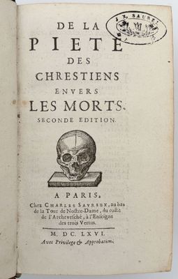 un vieux livre sur lequel repose un crâne, posé sur une table