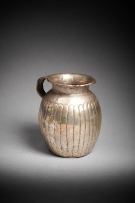an old silver vase sitting on top of a white table