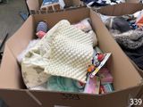 a cardboard box filled with clothes and a dog sleeping in it