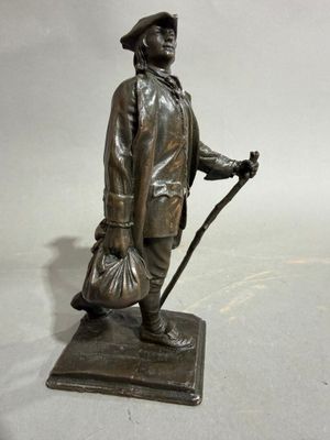 statue en bronze représentant un homme muni d'une canne et d'un chapeau, tenant un sac