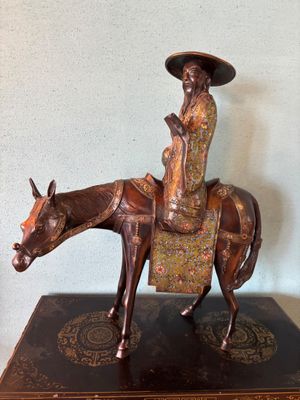 bronze statue of a woman riding a horse with a hat on her head