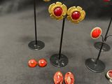 several pairs of gold and red earrings are displayed on a black surface
