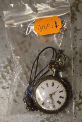 une petite montre de poche dans un sachet en plastique posé sur une table