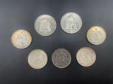 six different coins are arranged in a circle on a black surface