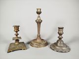 three antique brass candlesticks on a white background