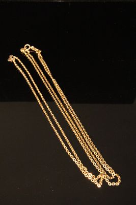 a close up of a gold necklace on a black surface
