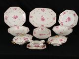 a group of pink and white plates and bowls on a black table