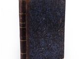 an old book with a blue cover on a white surface