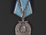 an old medal with a blue ribbon and a silver clasp
