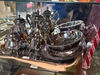 un plateau en argent sur lequel sont disposés des couverts, présenté dans une vitrine