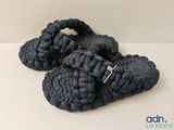 une paire de sandales noires posées sur une surface blanche