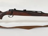 fusil exposé sur fond blanc, dans un présentoir en verre transparent
