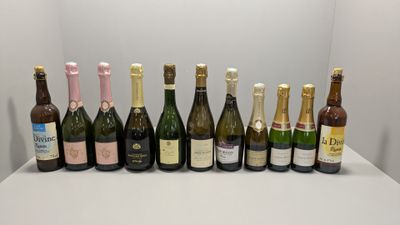 Des bouteilles de vin sont alignées sur une table devant un mur blanc.