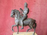 bronze statue of a man riding a horse on a marble base