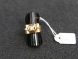 une bague noire et dorée sur laquelle est accrochée une étiquette blanche