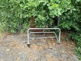 a metal bed frame sitting on the ground next to a bush