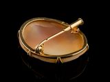 yellow gold plated broochle with a glass of wine on a black surface
