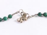 a close up of a green beaded necklace on a white surface