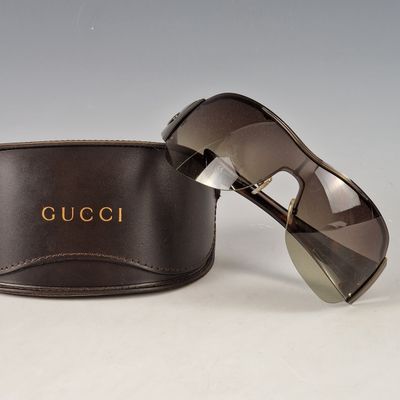 pair of gucci sunglasses with case on a white surface