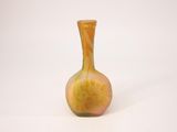 a yellow vase with a flower on it on a white surface